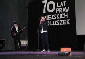 Zdjęcie uczniów występujących na scenie podczas obchodów 70-lecia Nadania Praw Miejskich Koluszkom w Miejskim Ośrodku Kultury w Koluszkach