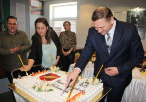 Zdjęcie Burmistrza Koluszek Waldemara Chałata krojącego tort dla mieszkańców Gminy Koluszki podczas obchodów 70-lecia Nadania Praw Miejskich Koluszkom w Miejskim Ośrodku Kultury w Koluszkach