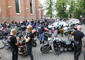 Zdjęcie uczestników oraz motocykli stojących przed kościołem pw. Niepokalanego Poczęcia NMP w Koluszkach podczas mszy świętej