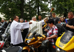 Zdjęcie księdza proboszcza święcącego uczestników oraz motocykle stojące przed kościołem pw. Niepokalanego Poczęcia NMP w Koluszkach