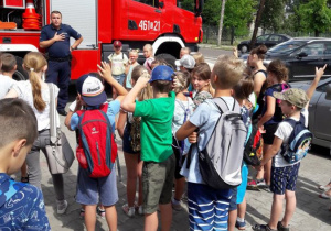 Zdjęcie uczestników III turnusu "Wakacji w mieście" podczas oglądania wozu stażackiego na parkingu MOK