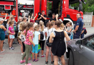 Zdjęcie uczestników III turnusu "Wakacji w mieście" podczas oglądania wozu stażackiego na parkingu MOK