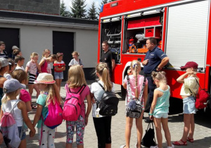 Zdjęcie uczestników III turnusu "Wakacji w mieście" podczas oglądania wozu stażackiego na parkingu MOK