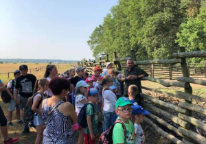 Zdjęcie przedstawiciela Leśnej Osady Edukacyjnej w Kole oprowadzającego uczestników zwiedzających obiekt w ramach 7 Kolorowej Lokomotywy