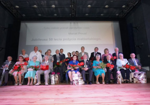 Zdjęcie wszystkich par małżeńskich obchodzących 50-lecie pożycia małżeńskiego siedzących na scenie w sali widowiskowej MOK