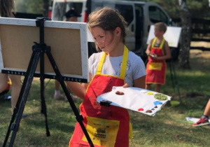 Zdjęcie uczestniczki warsztatów malarskich w Przedborskim Parku Krajobrazowym w ramach 7 Kolorowej Lokomotywy podczas malowania pracy