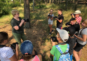 Zdjęcie pani instruktor oraz uczestników warsztatów fotograficznych w Przedborskim Parku Krajobrazowym w ramach 7 Kolorowej Lokomotywy