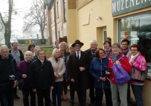 Zdjęcie słuchaczy Uniwersytetu Trzeciego Wieku Politechniki Łódzkiej oraz Mateusza Jaśkieiwcza przed Salą Muzealną MOK