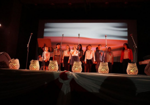 Zdjęcie wystepujących na scenie podczas koncertu patriotycznego pt. Tobie Ojczyzno w Miejskim Ośrodku Kultury w Koluszkach