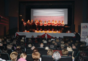 Zdjęcie wystepujących na scenie podczas koncertu patriotycznego pt. Tobie Ojczyzno w Miejskim Ośrodku Kultury w Koluszkach