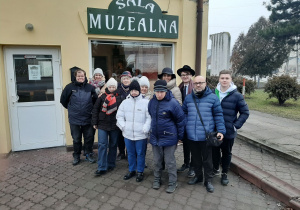 Zdjęcie członków Polskiego Stowarzyszenia na rzecz Osób z Niepełnosprawnością Intelektualną koło w Zgierzu oraz Matesza Jaśkiewicza przed Salą Muzealną MOK