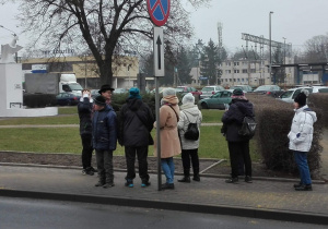 Zdjęcie członków Polskiego Stowarzyszenia na rzecz Osób z Niepełnosprawnością Intelektualną koło w Zgierzu oraz Matesza Jaśkiewicza przed pomnikiem Orła Białego przy ul. 3 Maja