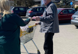 Zdjęcie Dyrektor MOK Elżbiety Przywara wręczającej maseczkę ochronną mężczyźnie