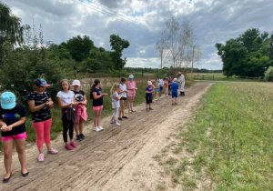 Zdjęcie przedstawia dzieci podczas warsztatów "Od ziarenka do bochenka" w Zagrodzie Edukacyjnej Konarzew Stajnia Lusi. Dzieci sieją ziarna na polu.