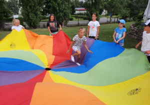 Zdjęcie przedstawia uczestników I turnusu Wakacji w mieście podczas zabawy z chustą animacyjną