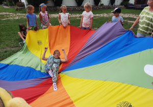 Zdjęcie przedstawia uczestników I turnusu Wakacji w mieście podczas zabawy z chustą animacyjną