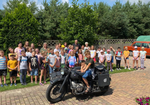 Zdjęcie przedstawia uczestników II turnusu, wychowawców, dyrektor MOK oraz Pana Pawła Swęda pozujących do pamiątkowego zdjęcia w towarzystwie zabytkowego motocykla w Zalesiu