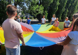 Zdjęcie przedstawia uczestników II turnusu Wakacji w mieście podczas zabawy z chustą animacyjną