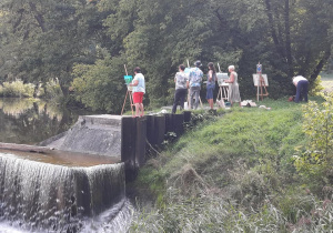 Zdjęcie przedstawia instruktora oraz uczestników artystycznego pleneru malarskiego w ramach warsztatów "Animacje na wakacje" podczas malowania prac w Lisowicach