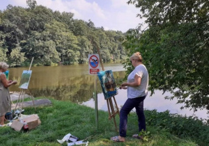 Zdjęcie przedstawia uczestników artystycznego pleneru malarskiego w ramach warsztatów "Animacje na wakacje" podczas malowania prac w Lisowicach