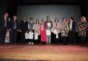 Zdjęcie przedstawia Jury, Przwodniczącego Rady Powiatu Łódzkiego Wschodniego, Kierownika Referatu Promocji Powiatu Łódzkiego Wschodniego, Dyrektor MOK oraz laureatów XXV Koluszkowskiego Przeglądu Piosenki w kategorii szkoły ponadpodstawowe i starsi do 22 roku życia