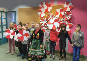 Zdjęcie przedstawia uczestników warsztatów patriotycznych „Polska znana i mniej znana” przebranych w stroje oraz prezentującyh prace plastyczne powstałe podczas warsztatów