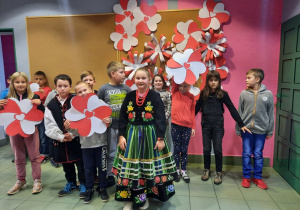 Zdjęcie przedstawia uczestników warsztatów patriotycznych „Polska znana i mniej znana” przebranych w stroje oraz prezentującyh prace plastyczne powstałe podczas warsztatów