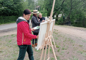 Zdjęcie przedstawia uczestników II artystycznego pleneru malarskiego w Lisowicach podczas malowania prac