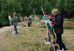 Zdjęcie przedstawia uczestników II artystycznego pleneru malarskiego w Lisowicach podczas malowania prac