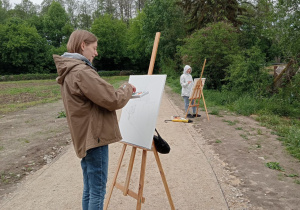 Zdjęcie przedstawia uczestników II artystycznego pleneru malarskiego w Lisowicach podczas malowania prac