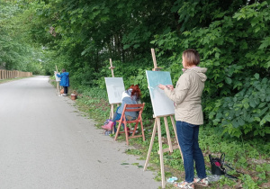 Zdjęcie przedstawia uczestników II artystycznego pleneru malarskiego w Lisowicach podczas malowania prac