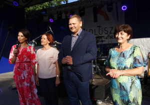 Zdjęcie przedstawia Burmistrza Koluszek Waldemara Chałata, Przewodniczącej Rady Miejskiej w Koluszkach Anny Szostak, Zastępcy Burmistrza Koluszek Krystyny Lewandowskiej oraz prowadzącej Dni Koluszek Magdaleny Libiszewskiej-Lisieckiej podczas przywitania uczestników imprezy masowej na scenie Amfiteatru Parku Miejskiego podczas Dni Koluszek 2022