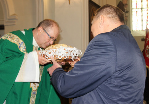 Zdjęcie Burmistrza Koluszek Waldemara Chałata składającego chleb dożynkowy na ręce księdza proboszcza podczas Mszy Świętej w Kościele pw. Niepokalanego Poczęcia NMP w Koluszkach